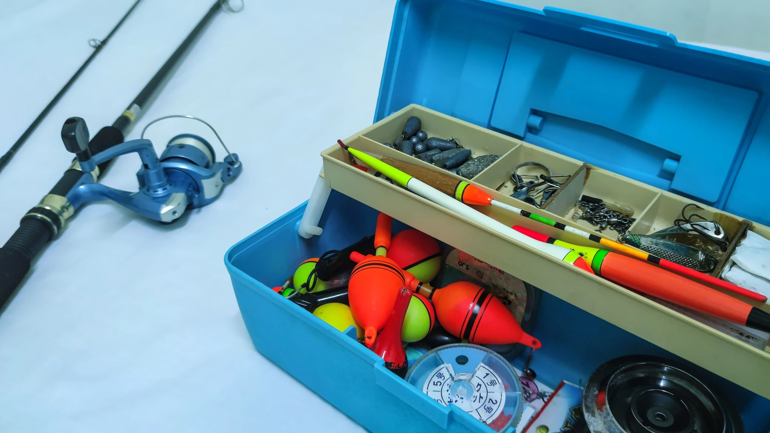 Close-up of fishing rod and organized tackle box with accessories