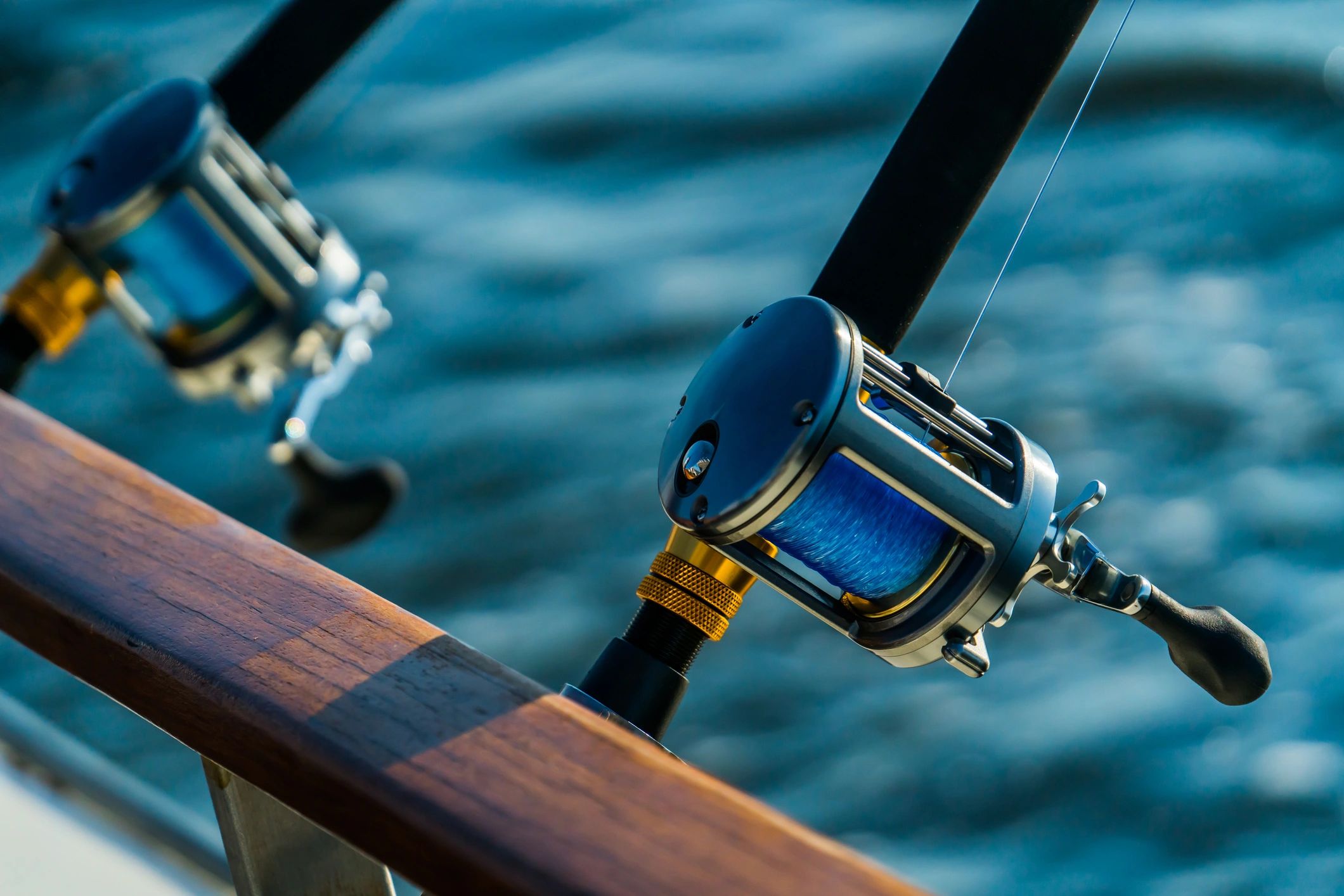 Fishing rod and reel resting on a boat at sunset